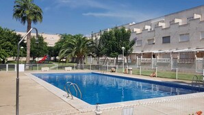 Une piscine rectangulaire avec un escalier en métal, entourée d’une clôture blanche.