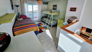 Une petite pièce comprenant des lits superposés, un bureau, une chaise et une petite table.