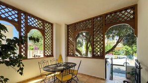 Un patio con una mesa redonda, sillas y un banco.