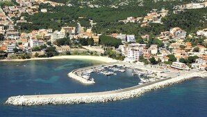 Un pueblo costero con un puerto deportivo, edificios residenciales y un puerto en curva.