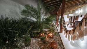 Un jardín tropical interior con una palmera, luces decorativas y una escalera de madera.