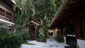 Un patio con una escalera central, rodeado de abundante vegetación y un camino empedrado.