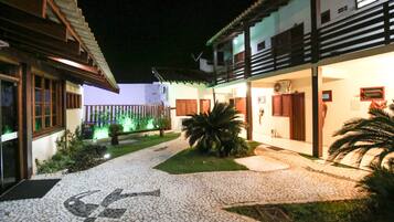 A courtyard with a cobblestone path, a palm tree, and a building with a balcony.