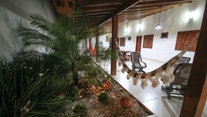 Una habitación con una hamaca, sillas y un pequeño jardín interior con plantas y esferas decorativas.