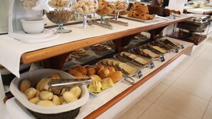 Un bufé con diferentes opciones de comida, incluyendo pan, pasteles y postres.