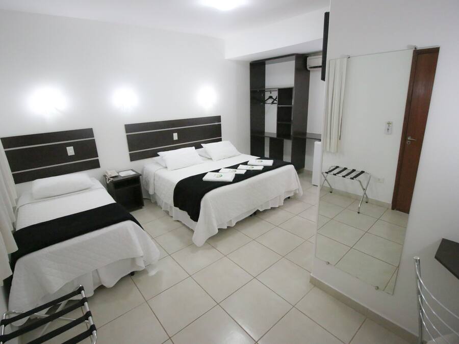 Een hotelkamer met twee bedden, een spiegel, een kledingkast en een klein tafeltje.