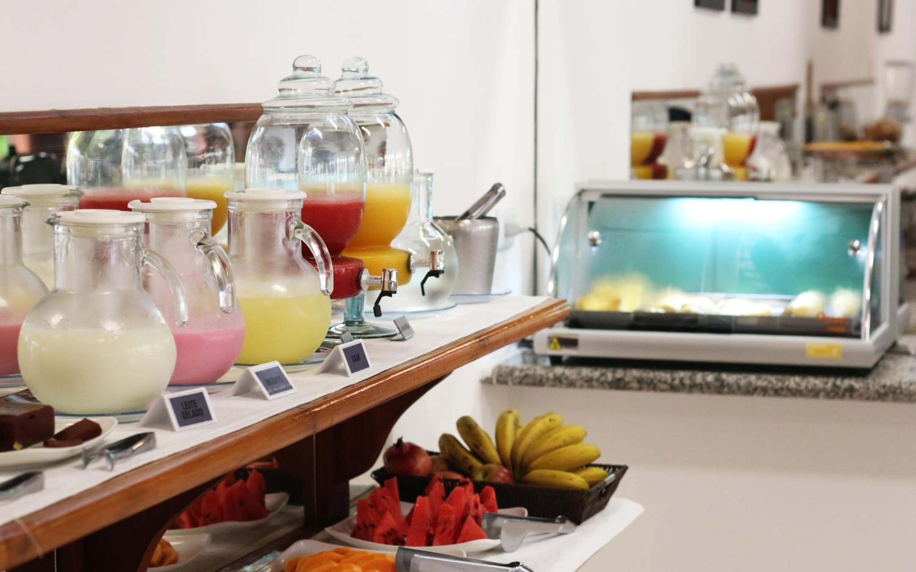 Un buffet proposant une variété de plats et de boissons, notamment un présentoir de fruits et un réfrigérateur contenant des plats préparés.
