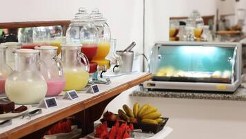 Un buffet proposant une variété de plats et de boissons, notamment un présentoir de fruits et un réfrigérateur contenant des plats préparés.
