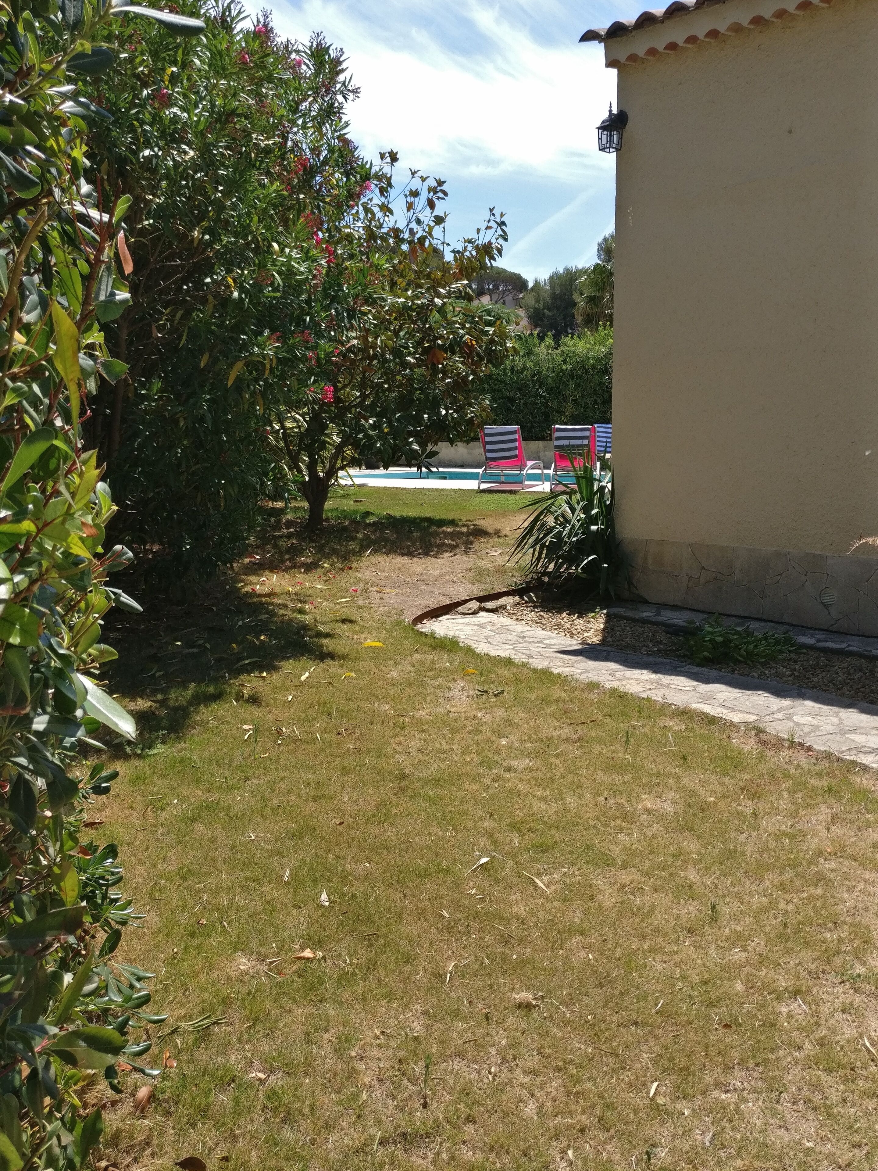 Una zona amb gespa, una piscina i dues cadires amb ratlles.