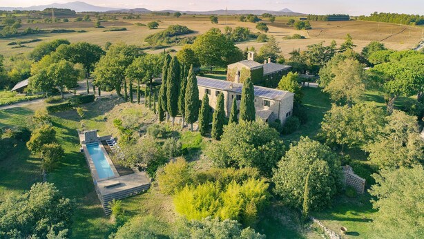 Una extensa propiedad con piscina, edificios de piedra y un paisaje verde exuberante.