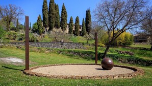 Un jardín circular con una escultura central, rodeado por un camino de grava y delimitado por un muro de piedra bajo.