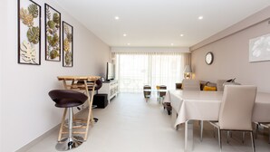 A modern living room with a dining area, a kitchen, and a balcony.