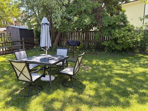 A patio with a table and chairs, surrounded by a wooden fence and greenery. - ￼Centrally Located Dewey Cottage - 1.5 Blocks to the Beach  (Dewey Beach)