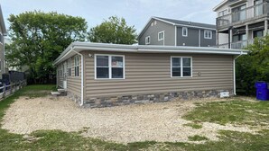A two-story house with a stone foundation and a gravel driveway.