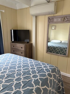 A hotel room with a bed, a dresser, a television, an air conditioning unit, and a mirror. - ￼Centrally Located Dewey Cottage - 1.5 Blocks to the Beach  (Dewey Beach)