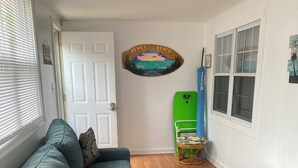 A living room with a teal sofa, a glass coffee table, and a wicker side table.