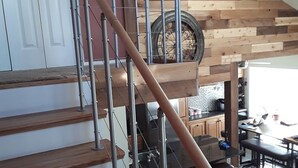 A staircase with metal railings and wooden steps, leading to a room with a kitchen area visible in the background. - Clear Creek Retreat - Take a trip to the mountains (Georgetown)