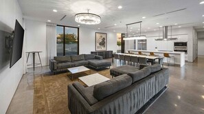 Relax in this stylish living space with a large sofa, dining area, and modern kitchen.