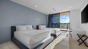Two beds with crisp linens, a desk, and a window offering a view of the outdoors.
