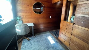 A wooden-paneled room with a round mirror, a desk, a chair, a dresser, and a small plant. - Simply Adorable Beach House - Sleeps 9, Near Beach & Town (Seaside)
