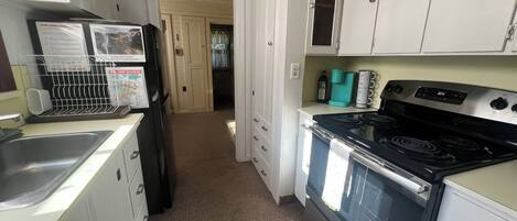 A kitchen with white cabinets, a stove, and a refrigerator.