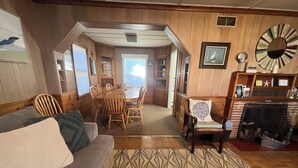 A cozy living room with a sofa, dining table, and chairs. There is a fireplace and a large mirror on the wall. - Simply Adorable Beach House - Sleeps 9, Near Beach & Town (Seaside)