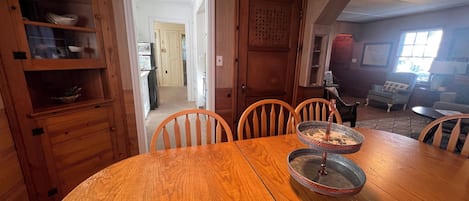 A dining area with a wooden table and chairs, a metal serving tray, and a wooden cabinet with shelves.