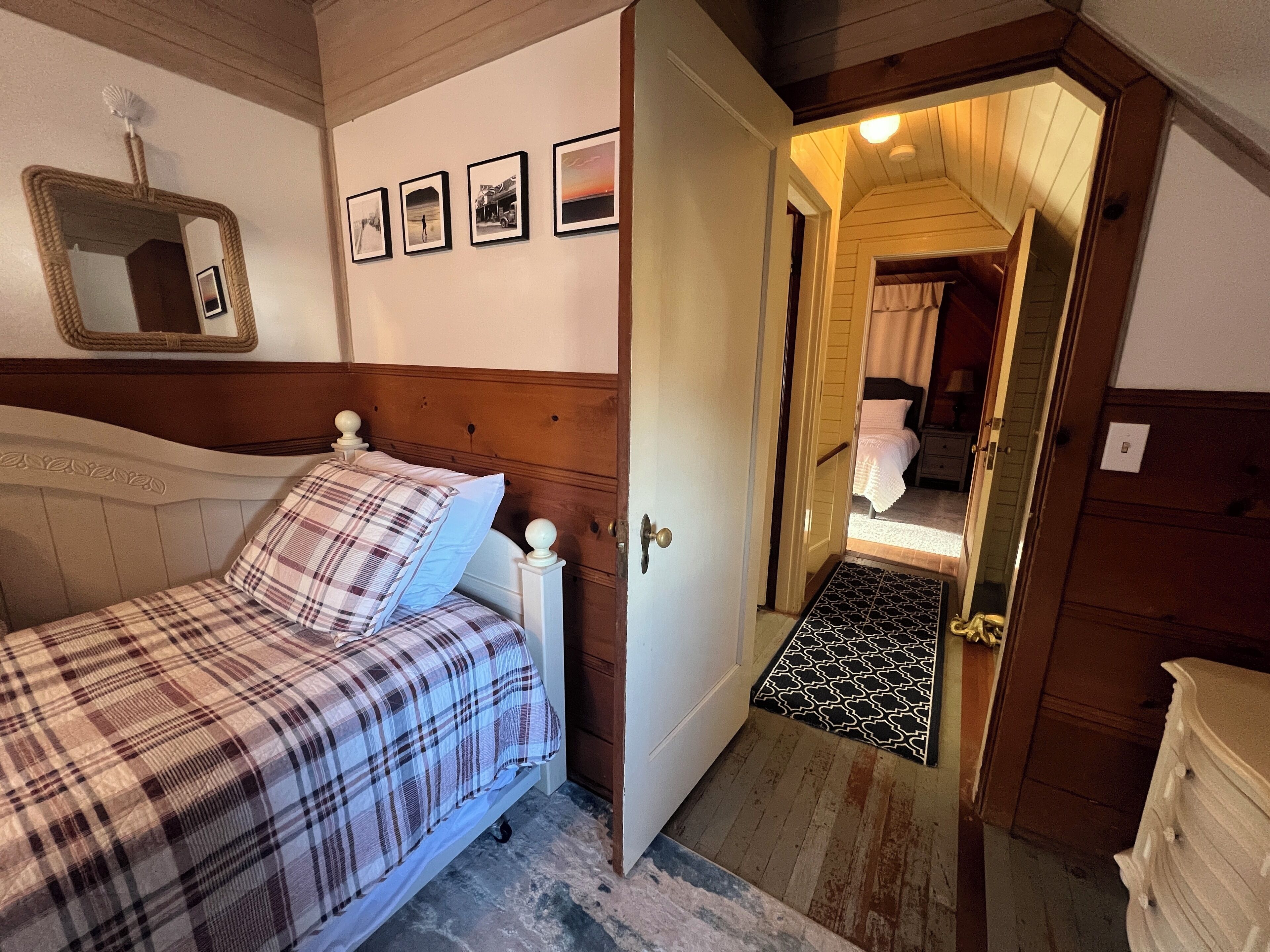 A bedroom with a bed, a mirror, and framed pictures on the wall.