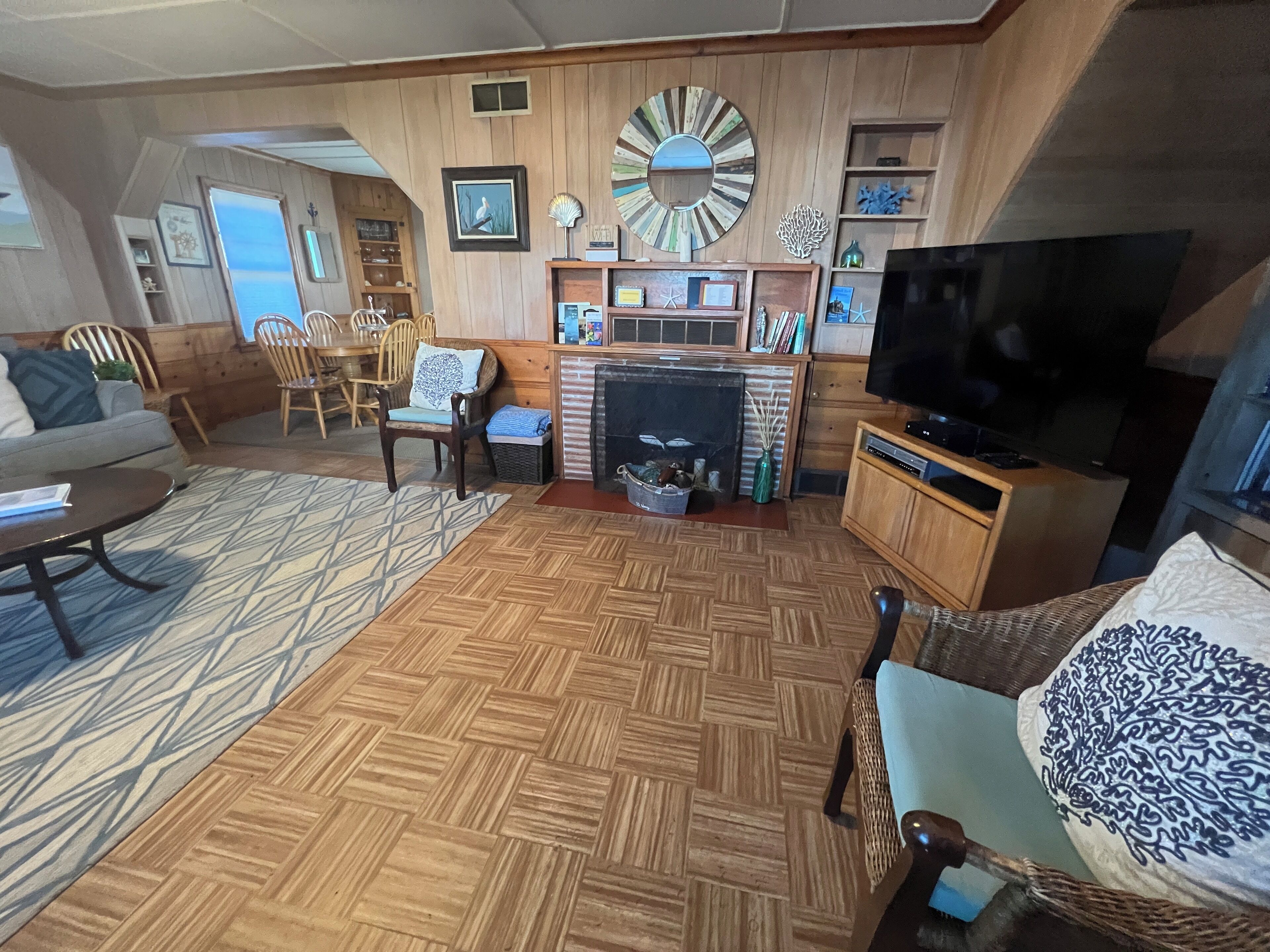 Un salon chaleureux avec un plancher en bois, une cheminée, un téléviseur et divers objets décoratifs.