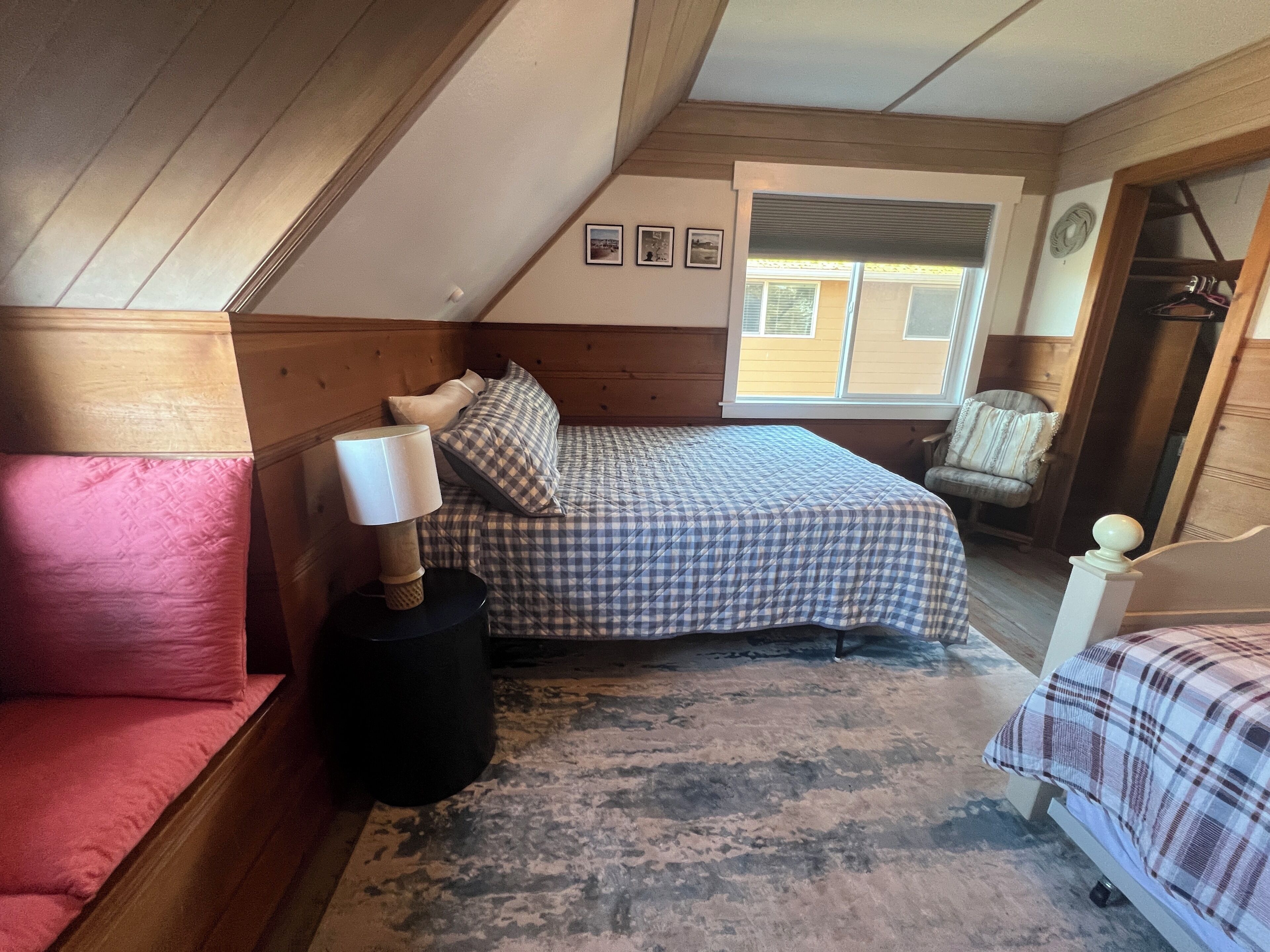 Une chambre confortable avec un lit, une table de chevet, une chaise et une fenêtre.