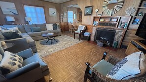 A cozy living room with a sofa set, a round coffee table, and a fireplace. - Simply Adorable Beach House - Sleeps 9, Near Beach & Town (Seaside)