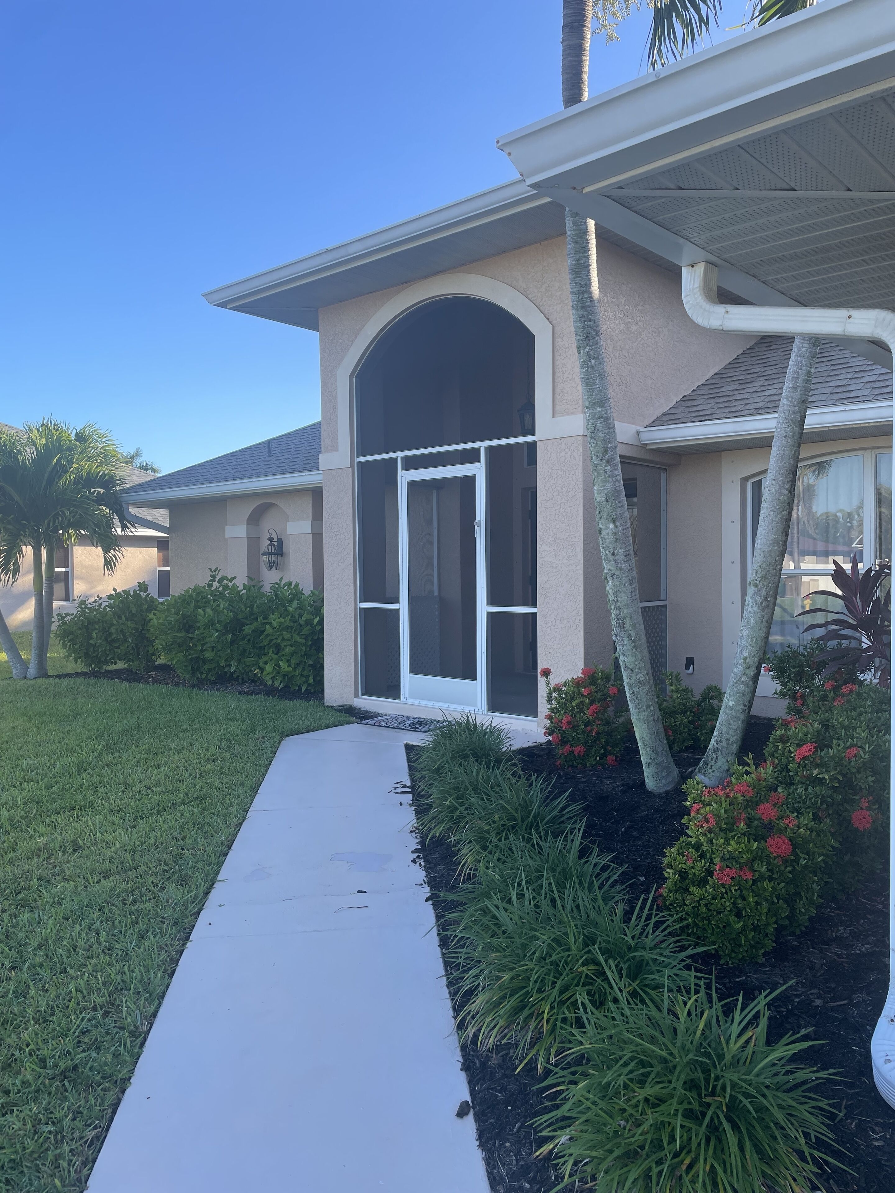 A residential house with a covered porch, a large arched entrance, and a well-maintained lawn.
