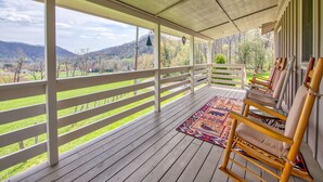 Eine überdachte Veranda mit Blick auf eine grüne Landschaft und Berge.