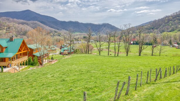 Eine rustikale Holzhütte mit grüner Dachdeckung, umgeben von einem üppigen Feld und einem Bergpanorama.