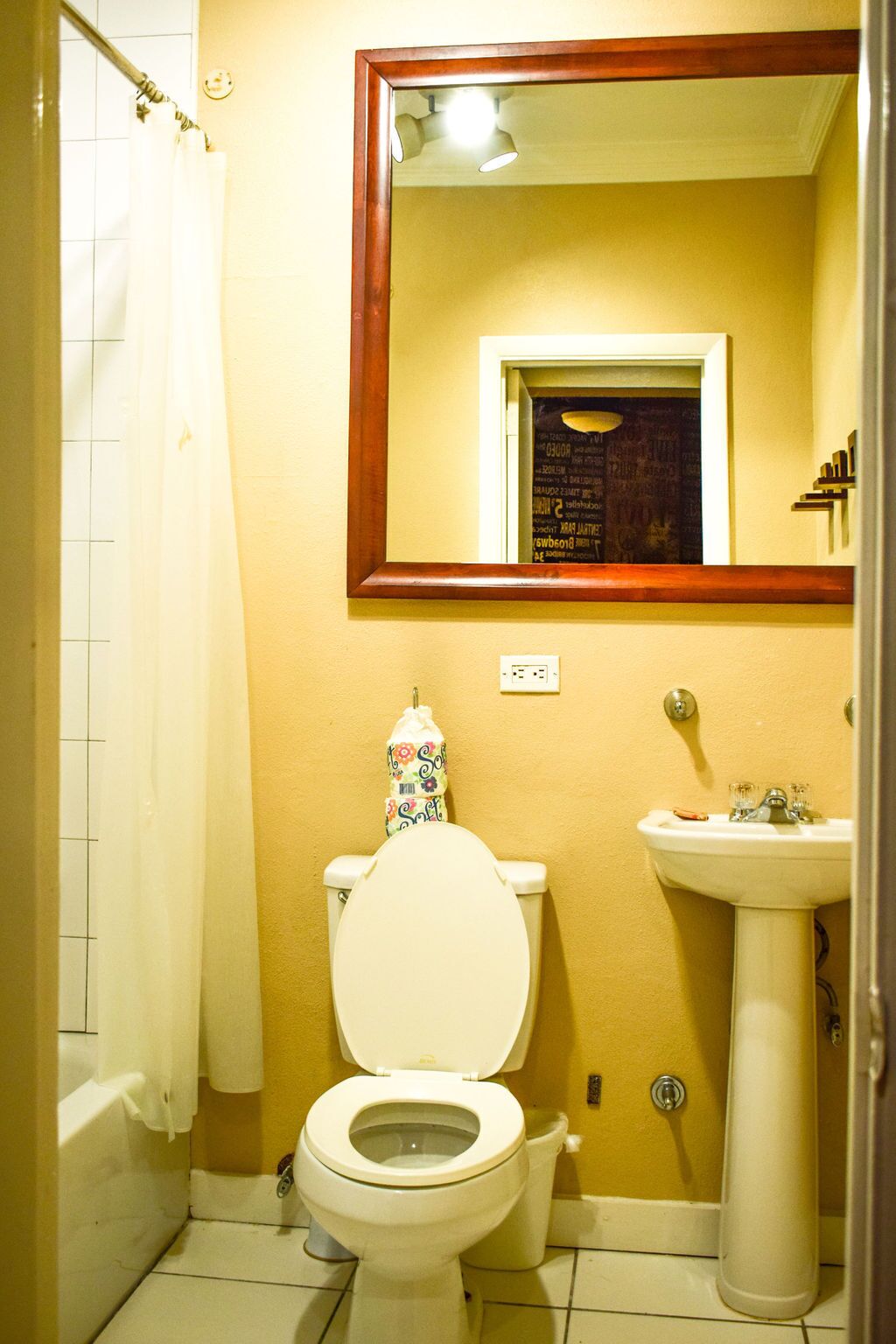 A bathroom with a toilet, sink, and a mirror above the sink.