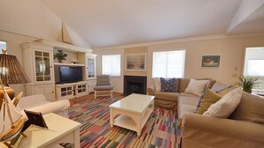 Ein Wohnzimmer mit Fernseher, Sofa, Sessel und einem gemusterten Teppich.