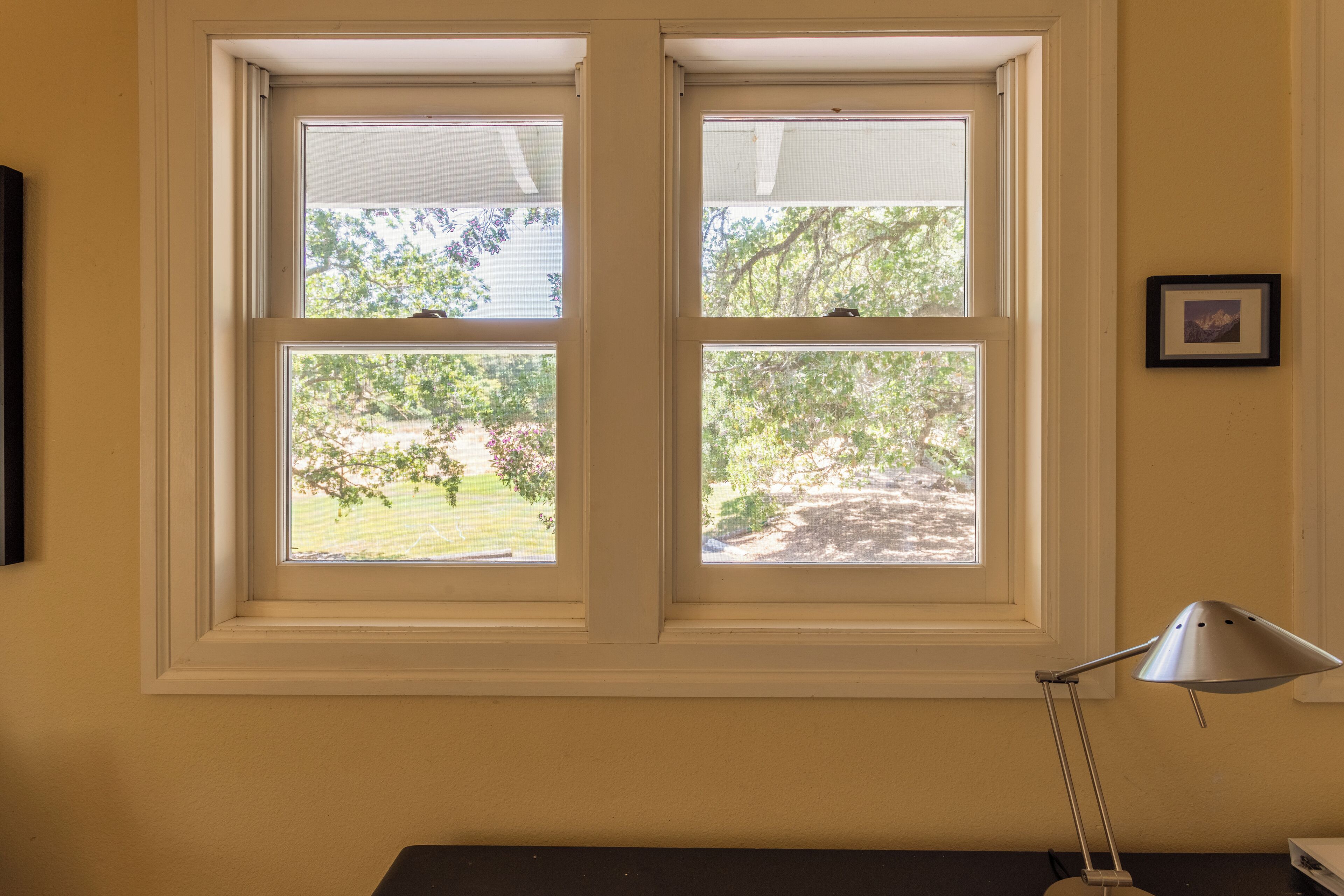 A room with a large window, a desk, and a lamp.