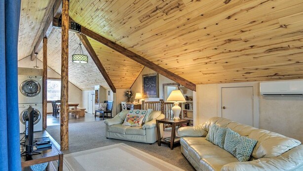 A cozy living room with a high wooden ceiling, a sofa, a coffee table, and a lamp.
