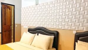 Habitación de hotel con cama, mesita de noche, puerta de madera y panel de pared con textura.