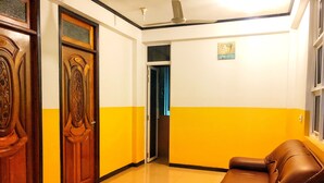 Un pasillo con un sofá de cuero marrón, puertas de madera y una pared amarillo y blanco.