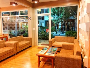 A cozy lobby with sofas and a coffee table, large windows with a view of the street, and a no-smoking sign on the wall. - Brize Inn (Hulhumalé)