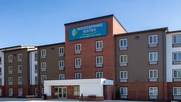 Un hotel de varios pisos con un cartel llamativo que indica 'Woodspring Suites', un hotel para estancias prolongadas.