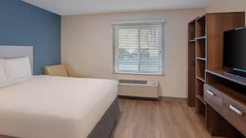 Ein Hotelzimmer mit Bett, Fernseher, Heizung und einem Fenster mit Jalousien.
