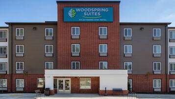 A multi-story hotel with a prominent sign for 'Woodspring Suites' indicating it is an extended stay hotel.