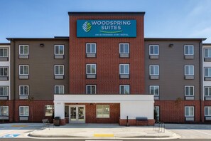 A multi-story hotel with a prominent sign for 'Woodspring Suites' indicating it is an extended stay hotel. - WoodSpring Suites Washington DC East Arena Drive (Hyattsville)