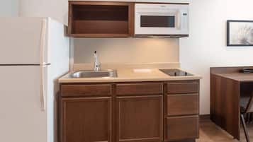 Una cocina compacta con microondas integrado, un fregadero y armarios de madera.