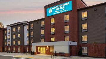 A multi-story hotel with a prominent sign for 'Woodspring Suites' indicating it is an extended stay hotel.