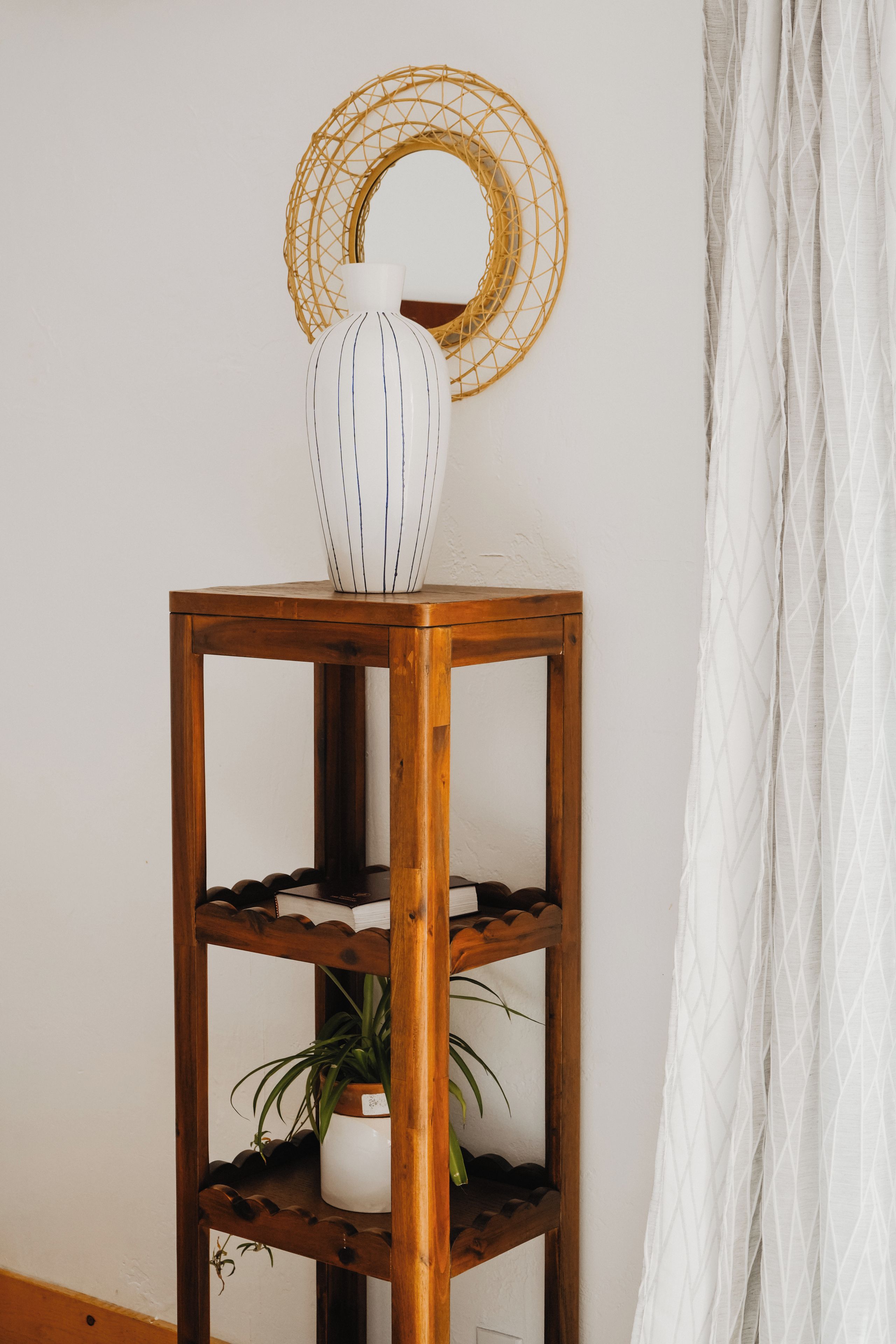 Una estantería de madera con un jarrón blanco y una planta en maceta.