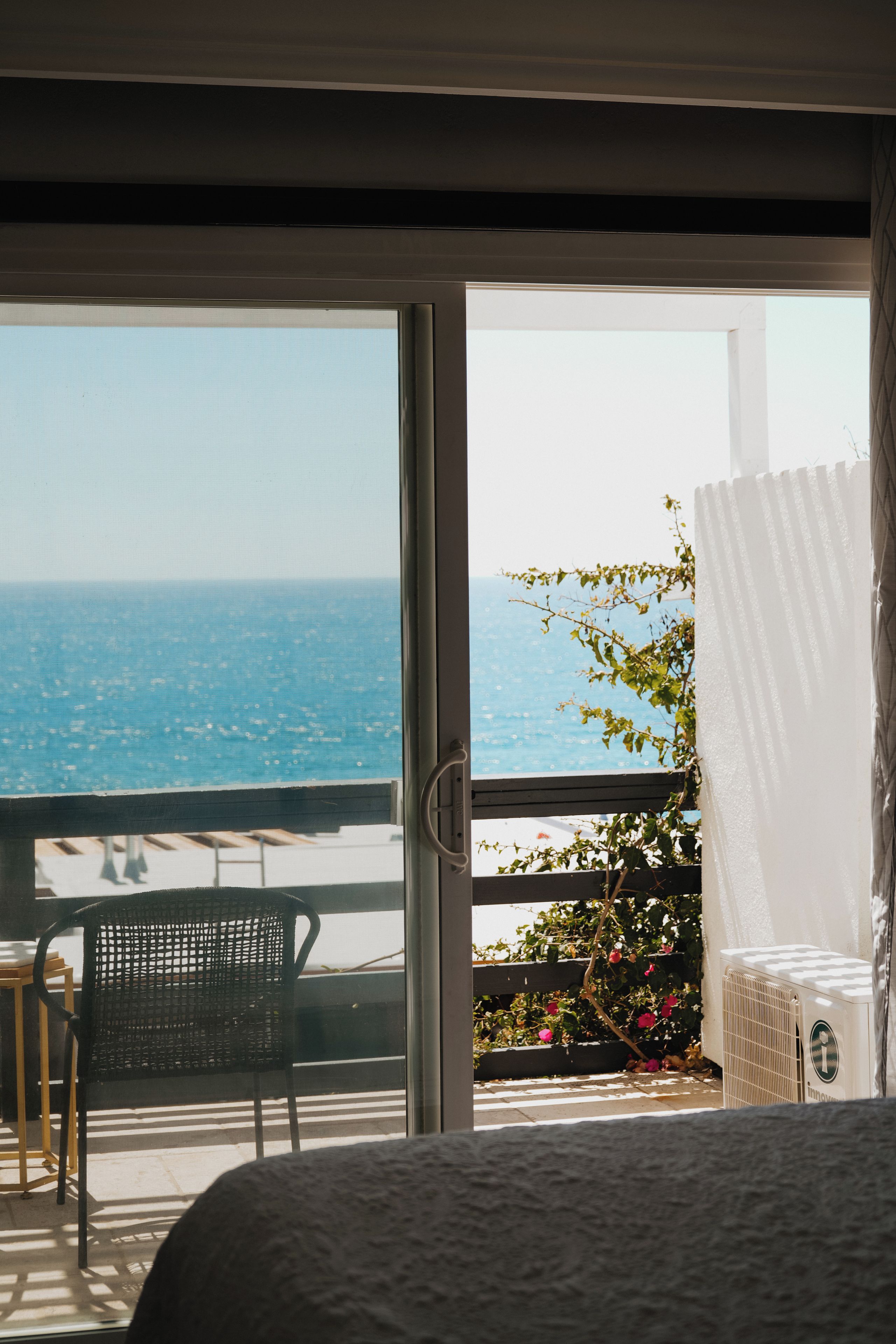Una habitación con vista al mar a través de un ventanal corredero.