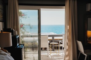 A hotel room with a view of the sea, a balcony with a table and chairs, and a bed with a lamp. - Laguna Cove Hotel (Laguna Beach)